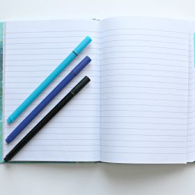 opened notebook with three assorted color pens